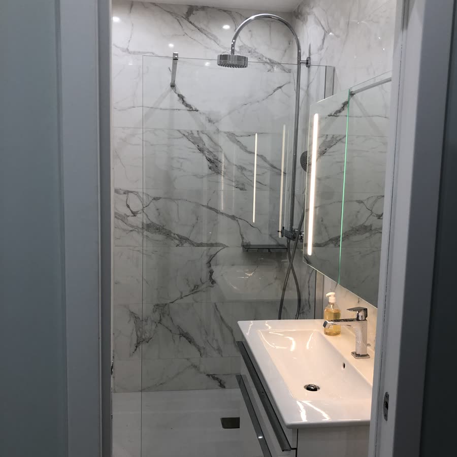 Salle d'eau en carrelage effet marbre : douche à l'italienne avec paroi vitrée, colonne de douche et meuble vasque suspendu